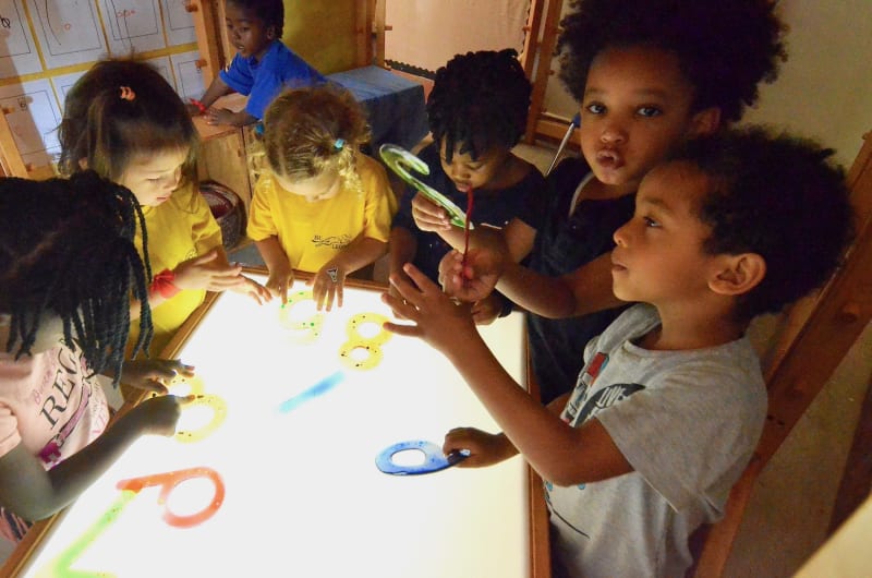 children looking at glowing screen and plastic numbers