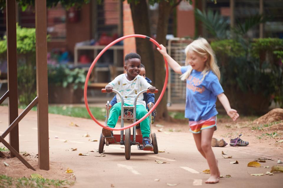 Young girl having fun with a hula hoop while two boys are cycling together on a bike